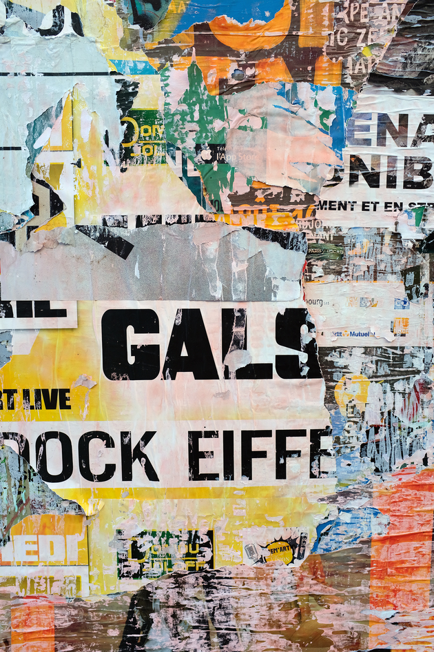 Posters on a grey concrete wall with 'GALS' in large, black letters in the middle